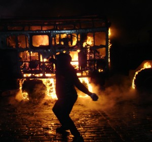 Violent protester hurling paving stone at police behind torched police bus barricade 11:46pm Jan 19, Hrushevskogo St., Kiev Michael Hammerschlag©2014